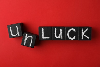 Black cubes with word UNLUCK on red background, flat lay