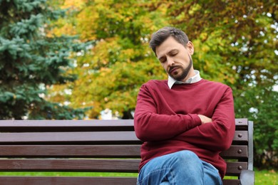 Photo of Tired man sleeping on bench in beautiful green park. Space for text