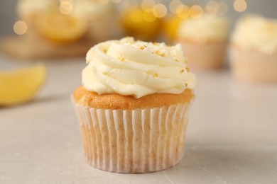 Tasty cupcake with cream and lemon zest on light table, closeup