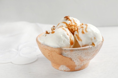 Photo of Tasty ice cream with caramel sauce and popcorn in bowl on table
