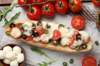 Tasty pizza toast and ingredients on wooden table, top view