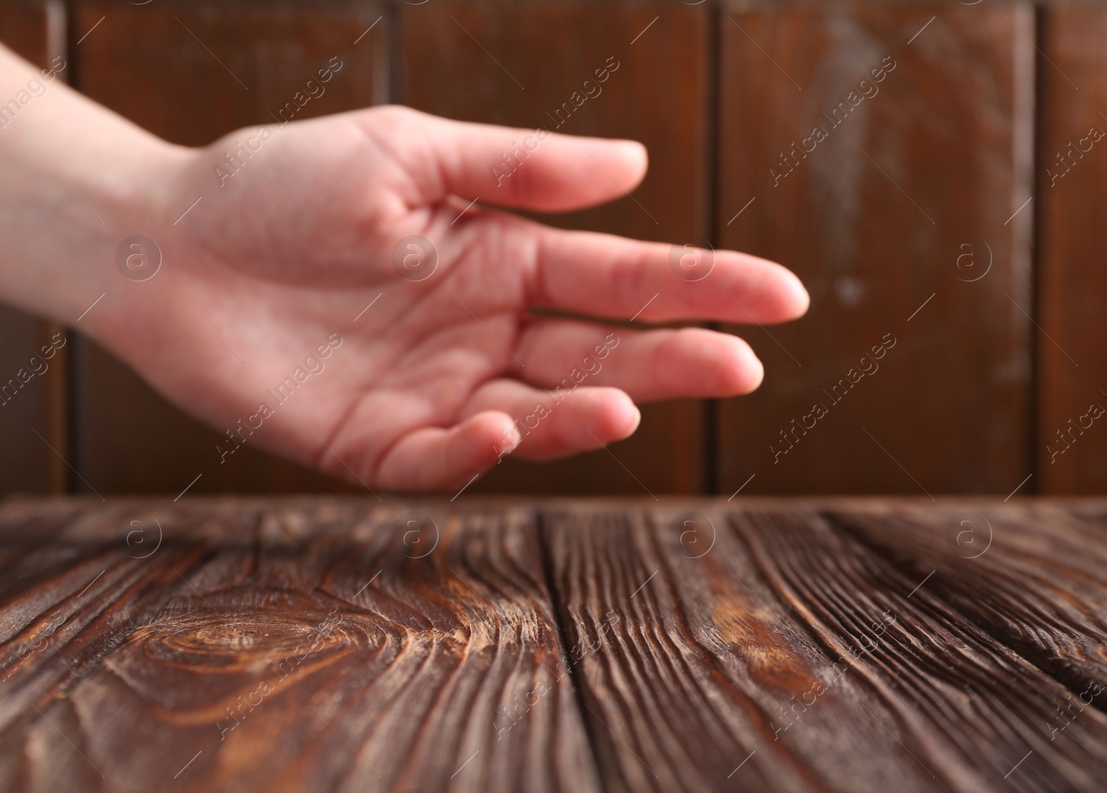 Photo of Woman holding hand above wooden table, selective focus. Space for text