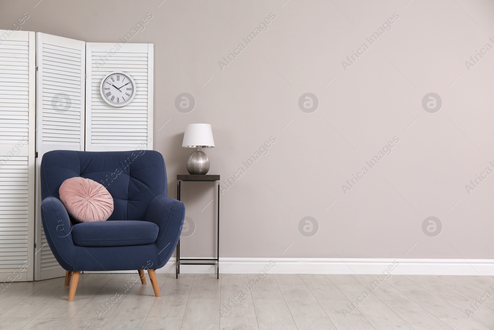 Photo of Comfortable armchair and decor near beige wall. Space for text