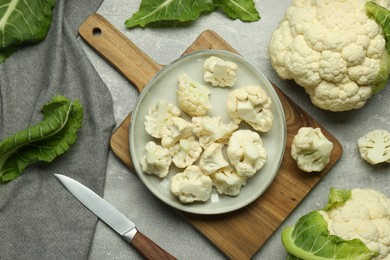 Photo of Cut and whole cauliflowers on grey table, flat lay