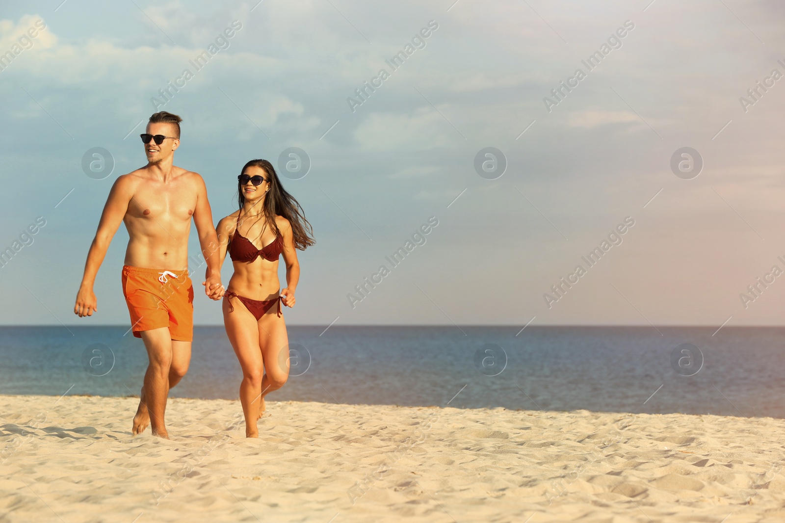 Photo of Young woman in bikini spending time with her boyfriend on beach. Lovely couple