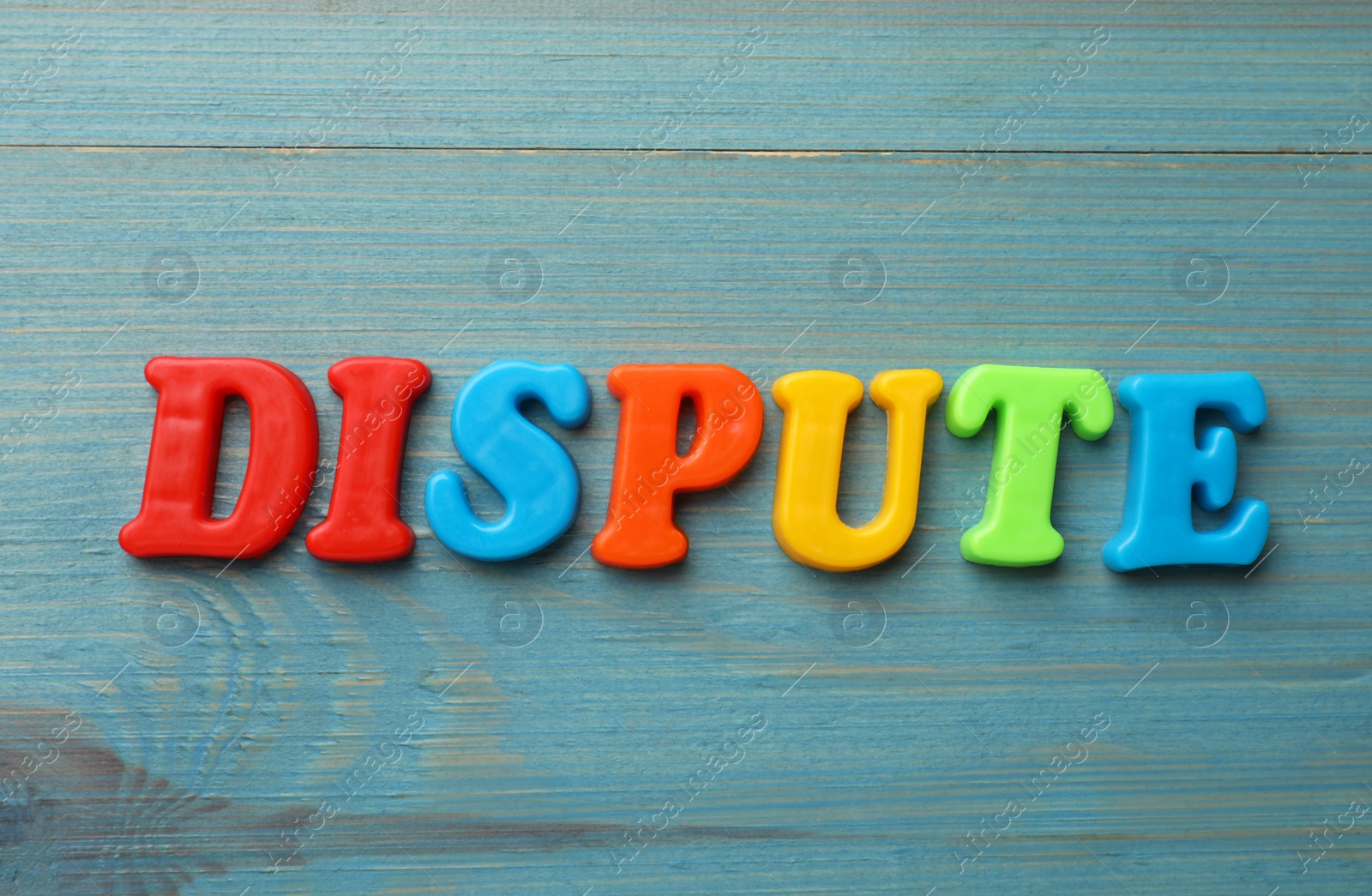 Photo of Word Dispute made of colorful letters on light blue wooden table, flat lay