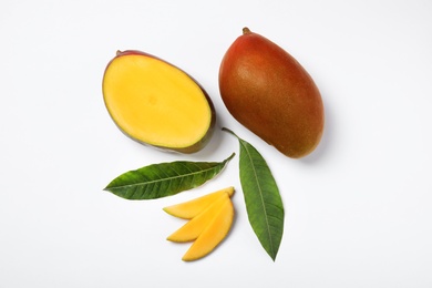 Photo of Tropical cut and whole mango with green leaves isolated on white, flat lay