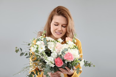 Photo of Beautiful woman with bouquet of flowers on grey background