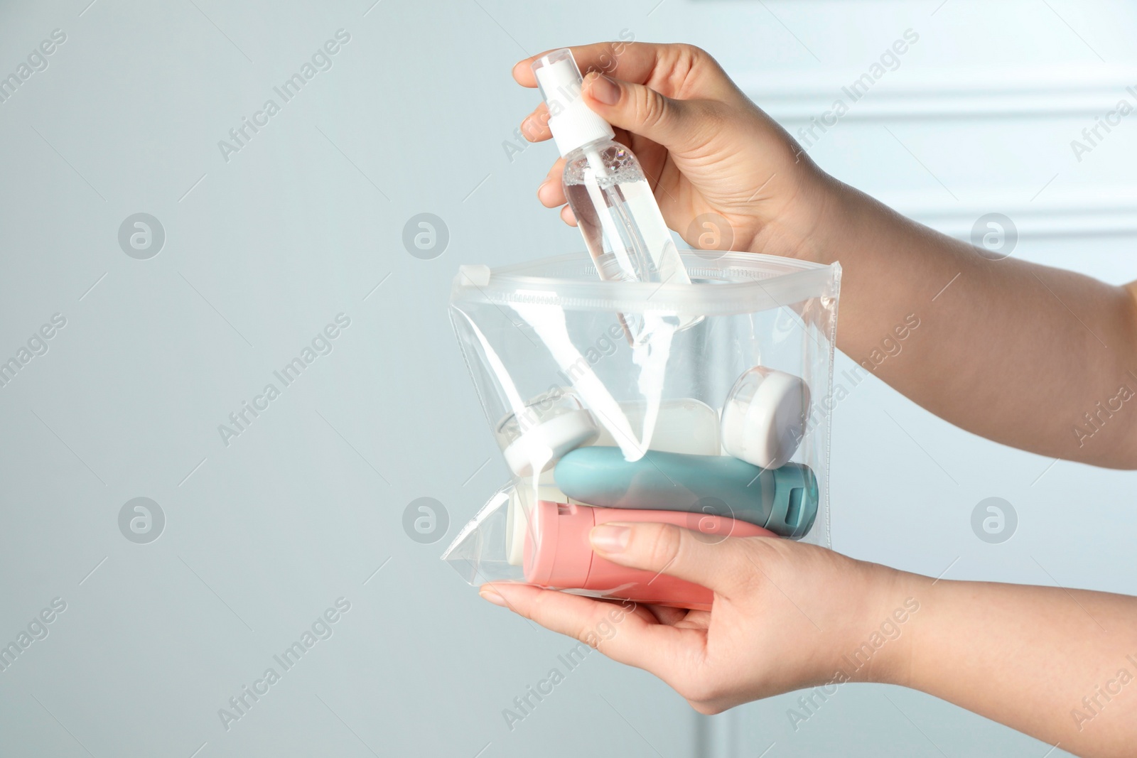 Photo of Woman packing cosmetic travel kit indoors, closeup. Space for text