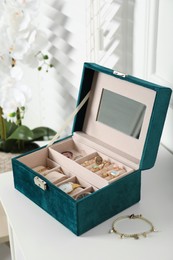 Elegant jewelry box with beautiful bijouterie and expensive wristwatches on white table in room