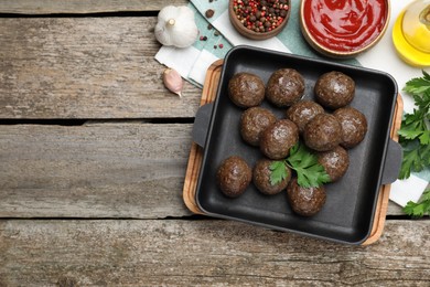 Photo of Tasty cooked meatballs with parsley on wooden table, flat lay. Space for text