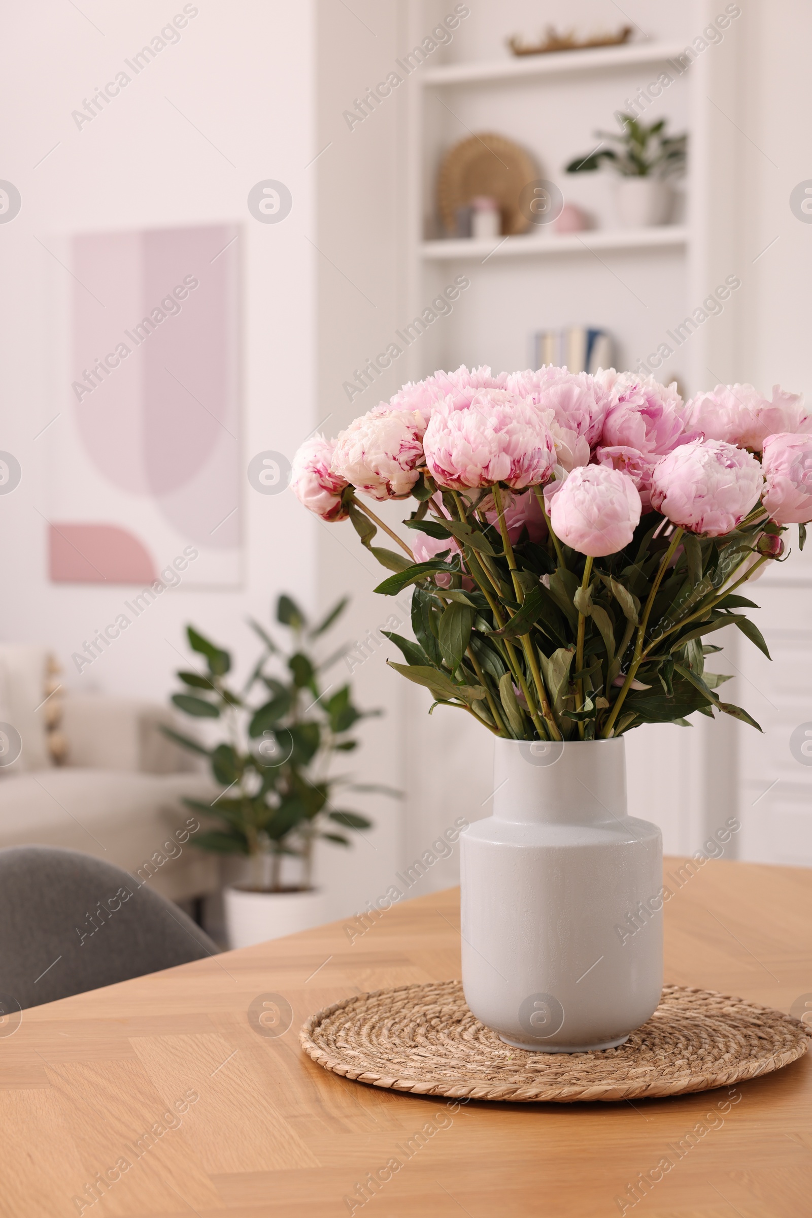 Photo of Vase with pink peonies on wooden table in dining room