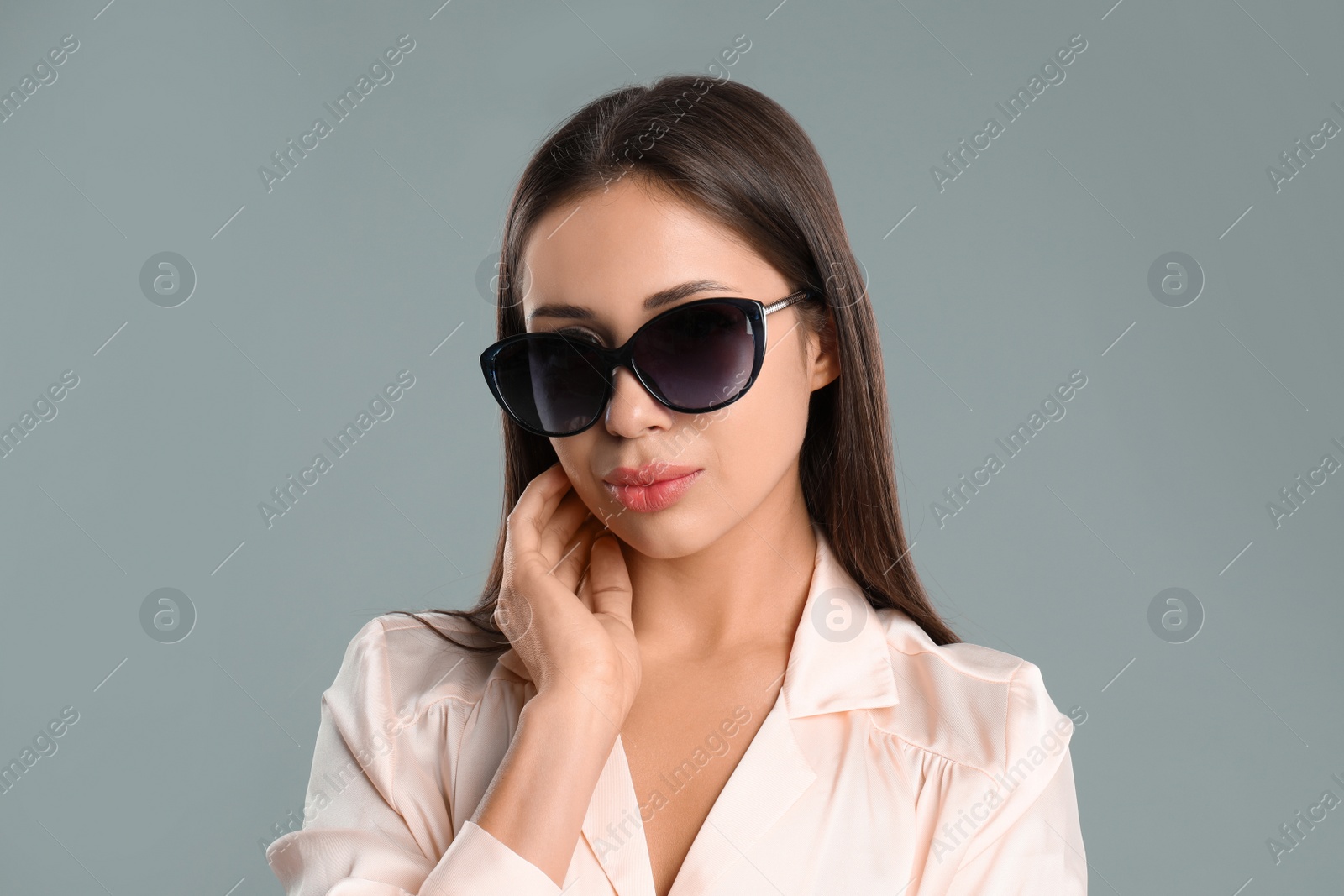 Photo of Beautiful young woman wearing sunglasses on grey background