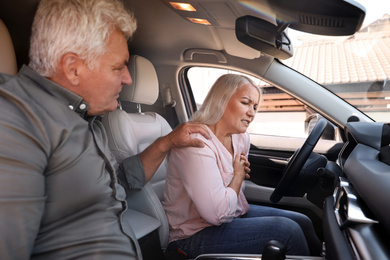 Image of Mature woman having heart attack near her husband in car 