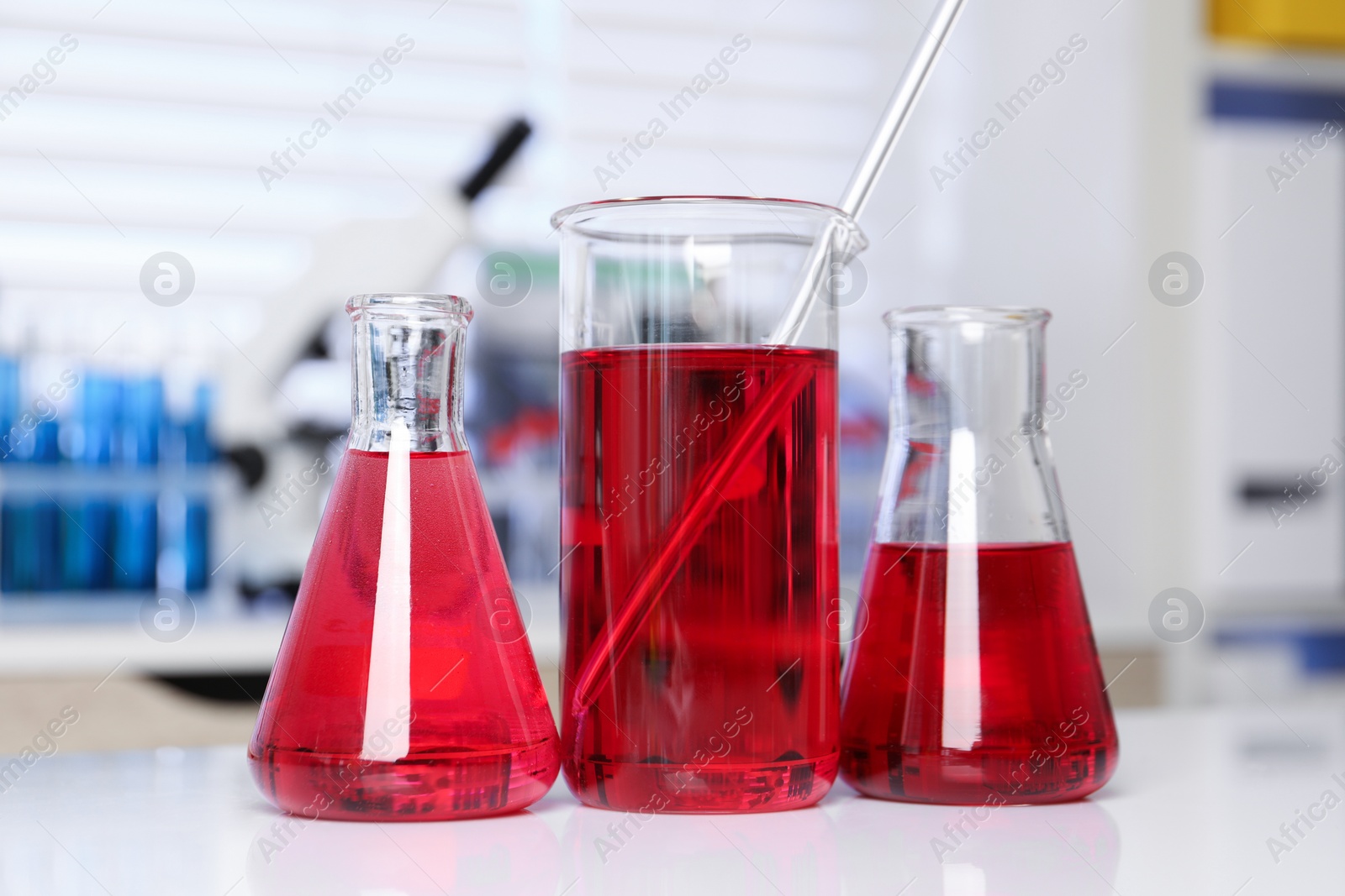 Photo of Laboratory analysis. Different glassware with red liquid on white table indoors