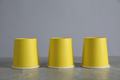 Shell game. Three yellow cups on grey marble table