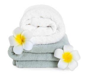 Photo of Different soft towels and plumeria flowers isolated on white