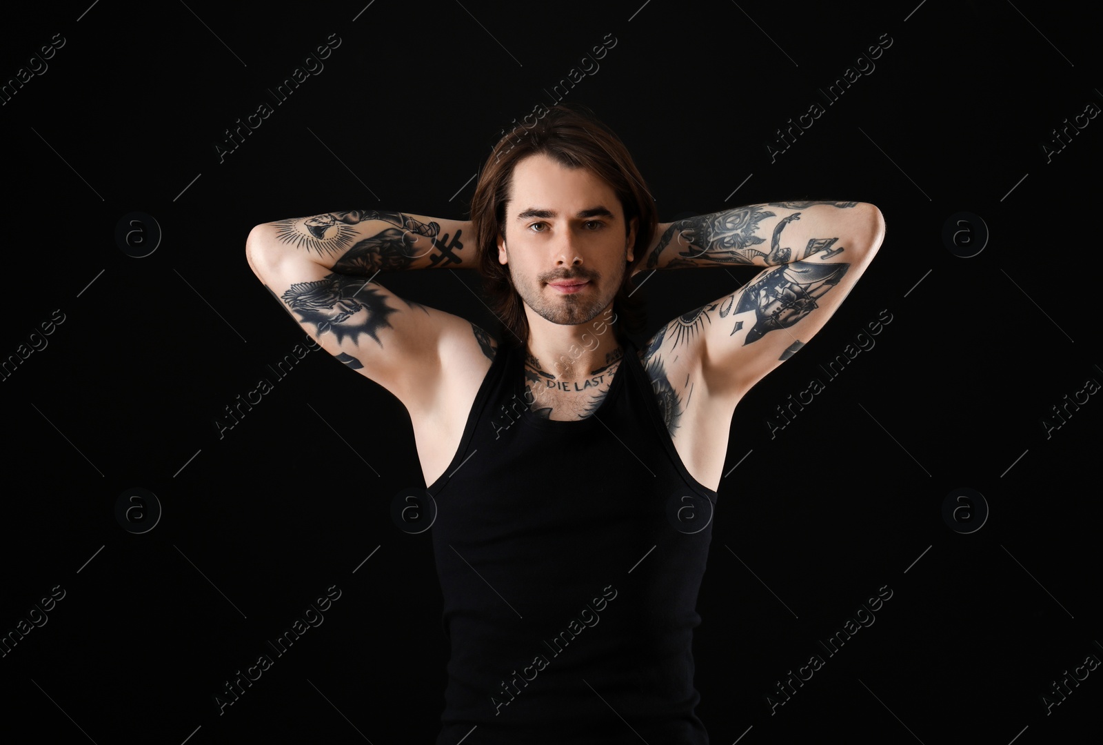 Photo of Young man with tattoos on body against black background