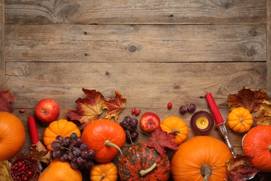 Photo of Flat lay composition with autumn leaves, berries and pumpkins on wooden table, space for text