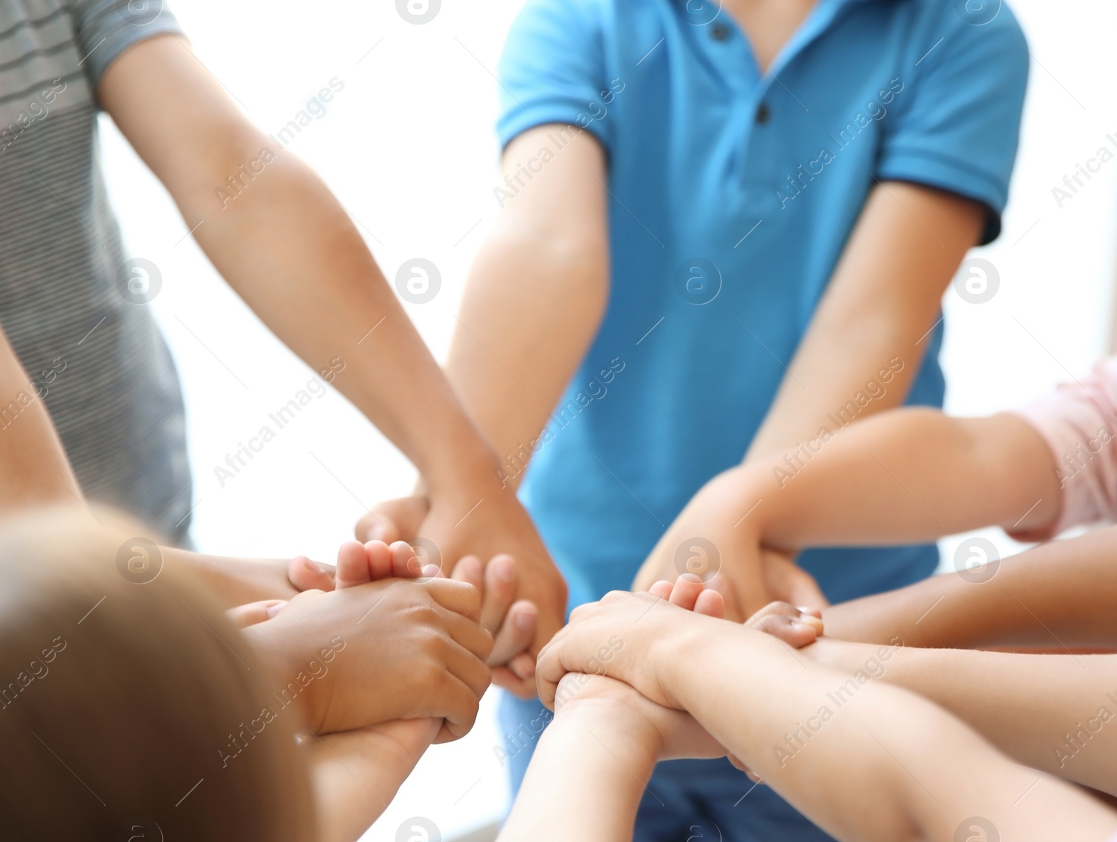 Photo of Little children holding their hands together on light background. Unity concept