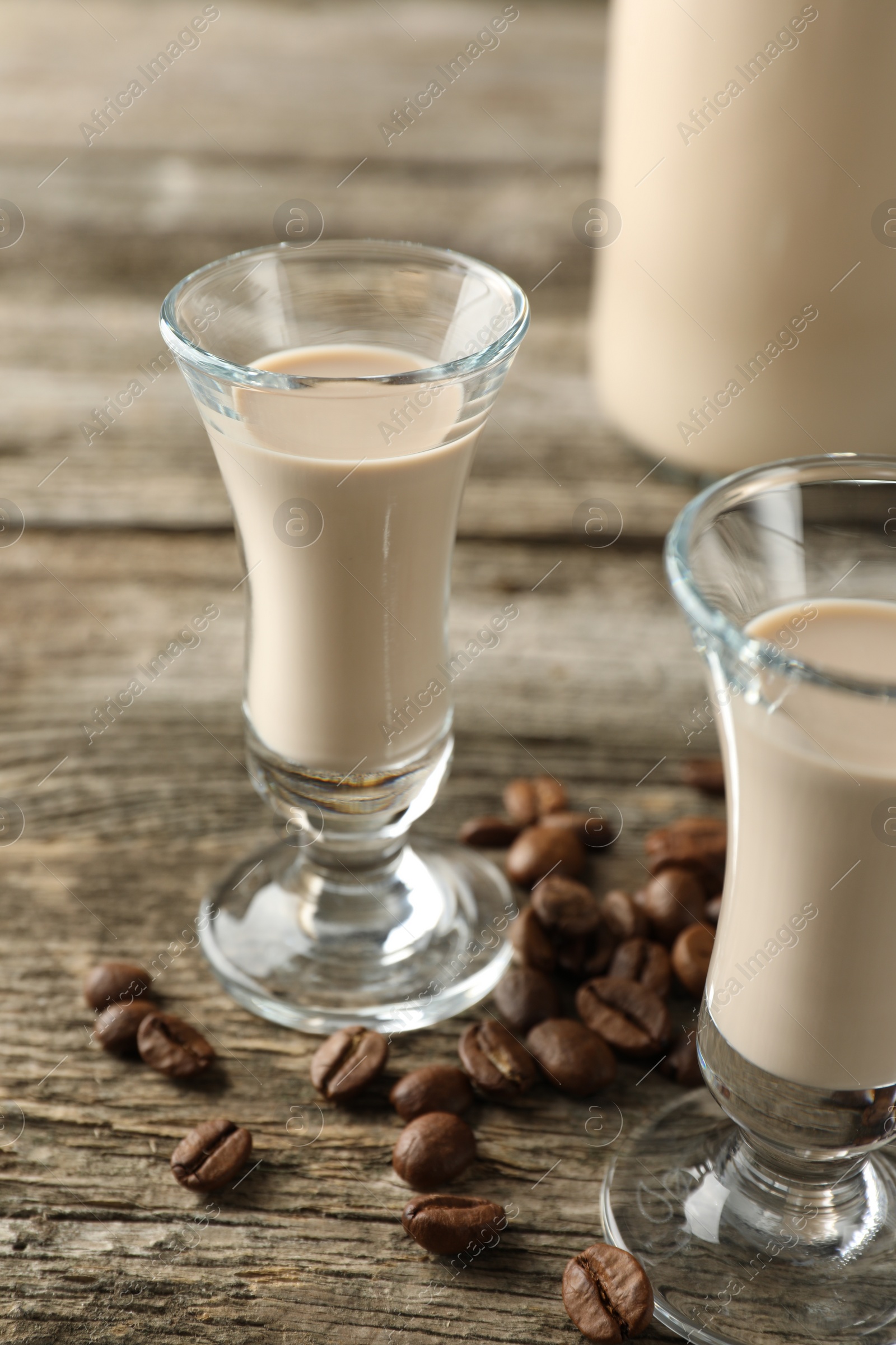 Photo of Coffee cream liqueur in glasses and beans on wooden table