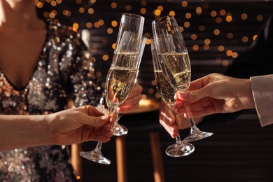 Photo of People clinking glasses of champagne indoors, closeup