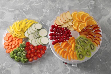Photo of Cut fruits, vegetables and dehydrator machine on grey marble table, flat lay
