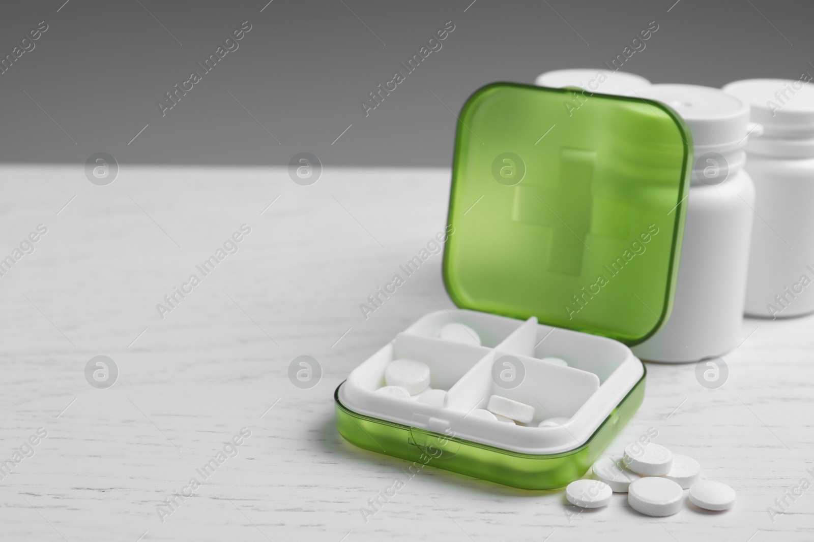 Photo of Pill box with medicaments on white wooden table. Space for text