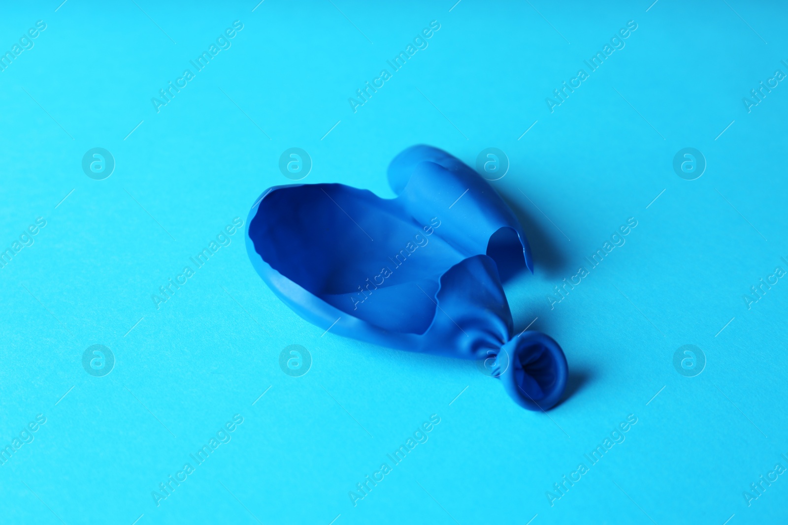 Photo of Popped blue latex balloon on color background