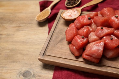 Photo of Cooking delicious goulash. Raw beef meat with spices on wooden table, closeup. Space for text