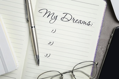 Image of Notebook with dreams list on table, flat lay 