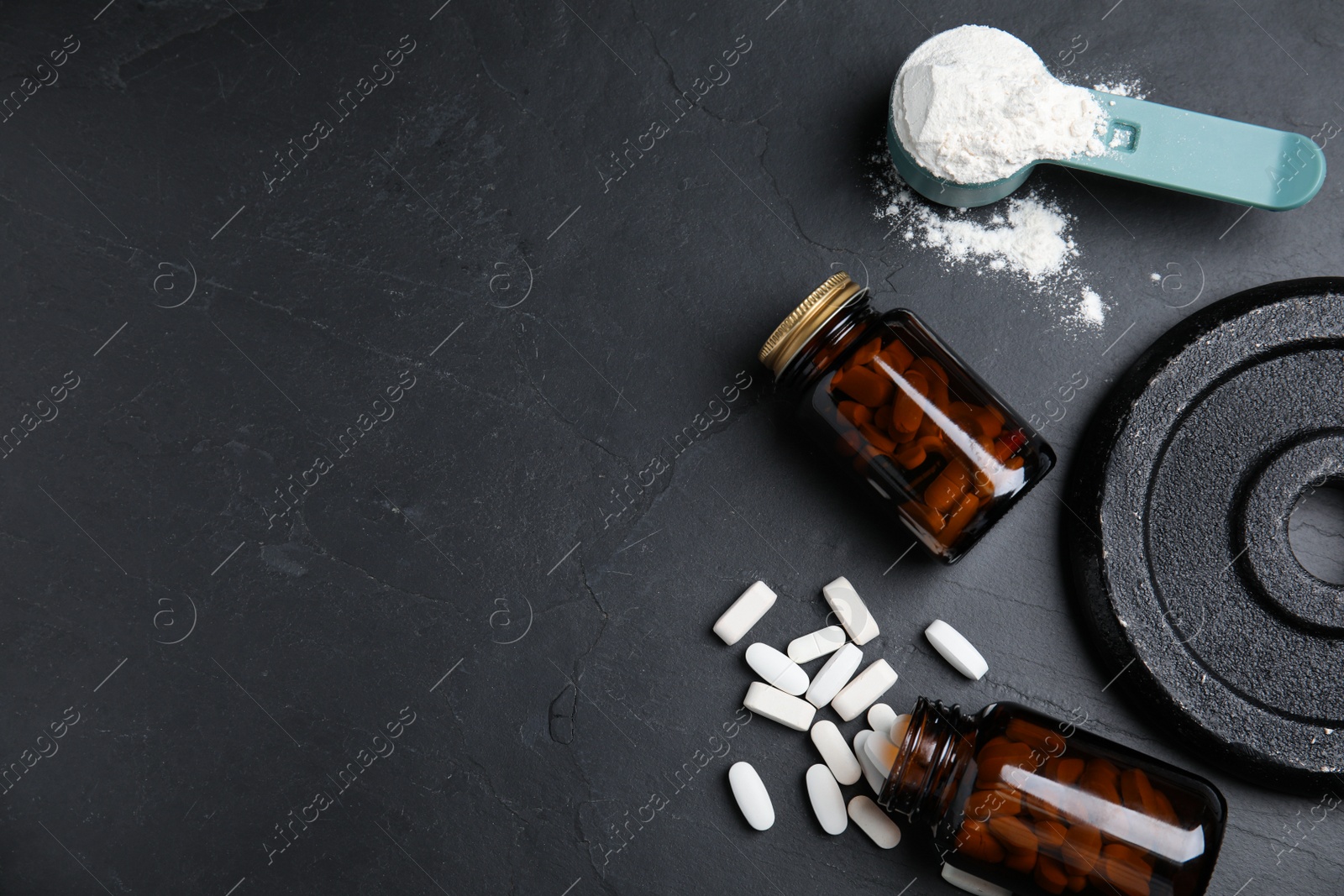 Photo of Pills, measuring scoop of amino acids powder and weight plates on black table, flat lay. Space for text