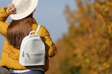Photo of Young woman with stylish backpack on autumn day, back view. Space for text