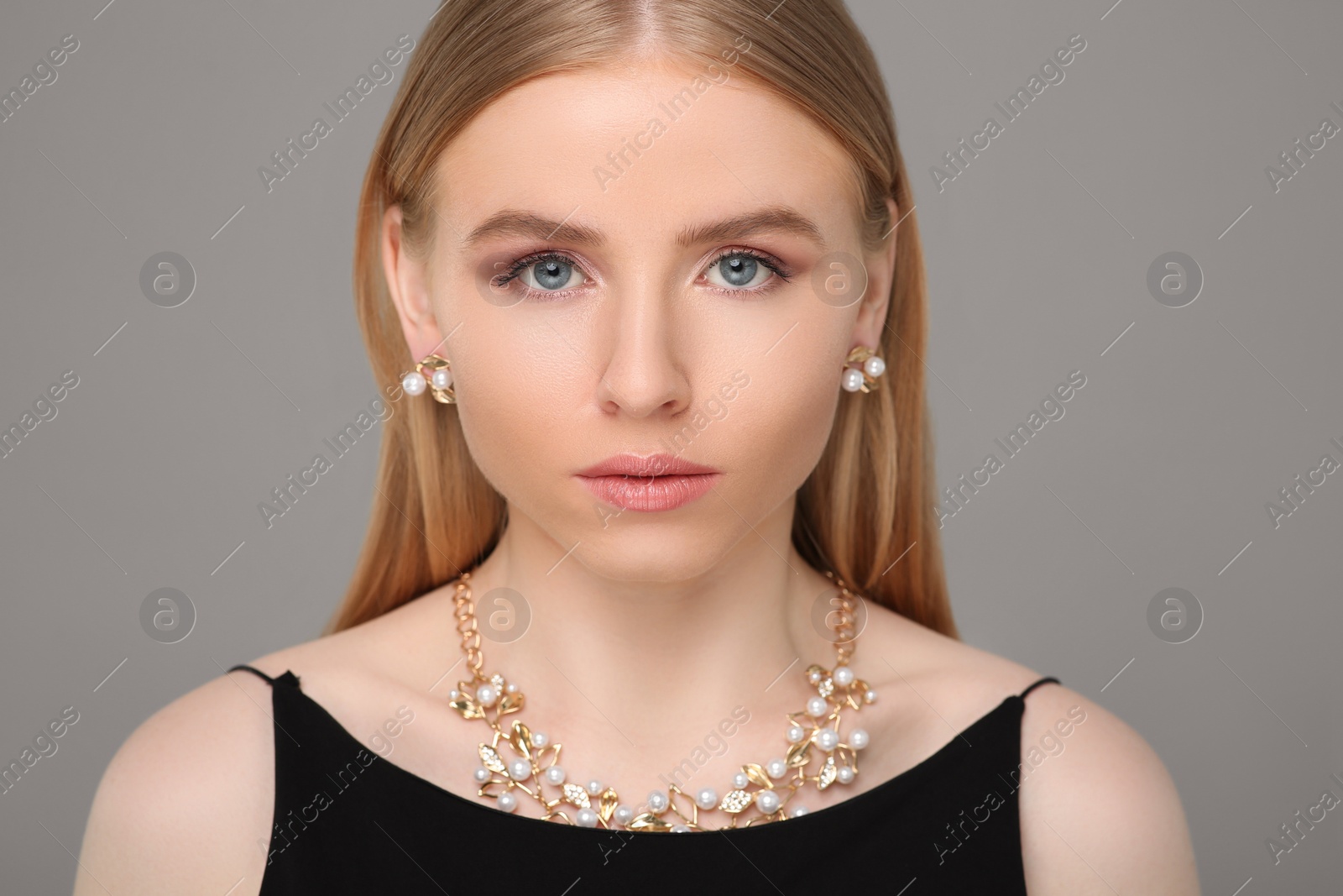 Photo of Beautiful young woman with elegant jewelry on gray background