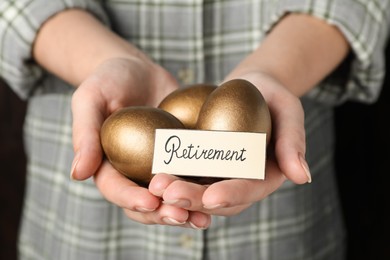 Photo of Woman holding golden eggs and card with word Retirement, closeup. Pension concept