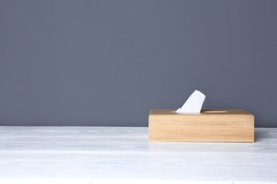 Photo of Napkin holder with paper serviettes on table against color background. Space for text