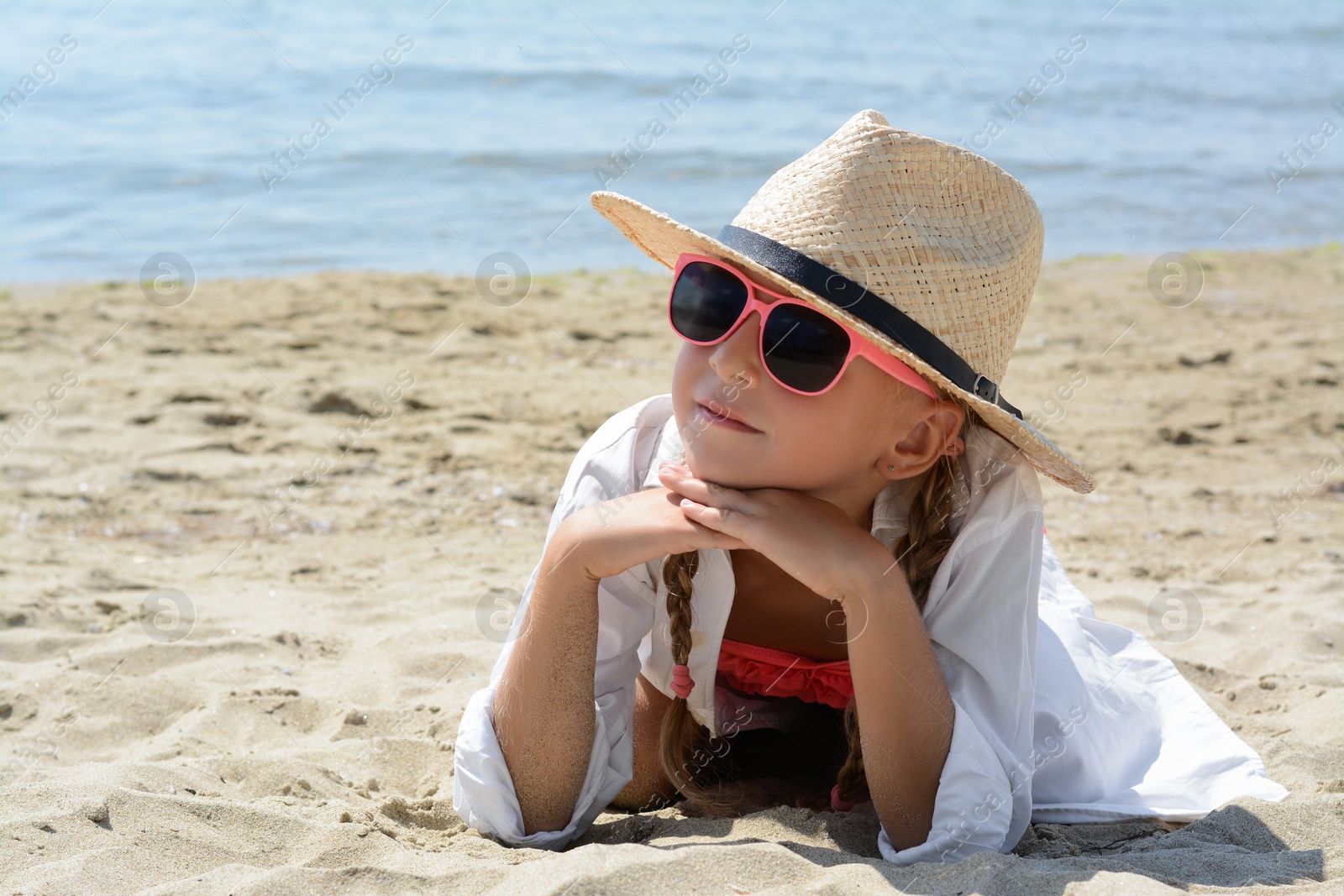 Photo of Little girl wearing sunglasses and hat at beach on sunny day. Space for text