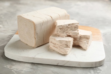 Board with pieces of compressed yeast on grey table