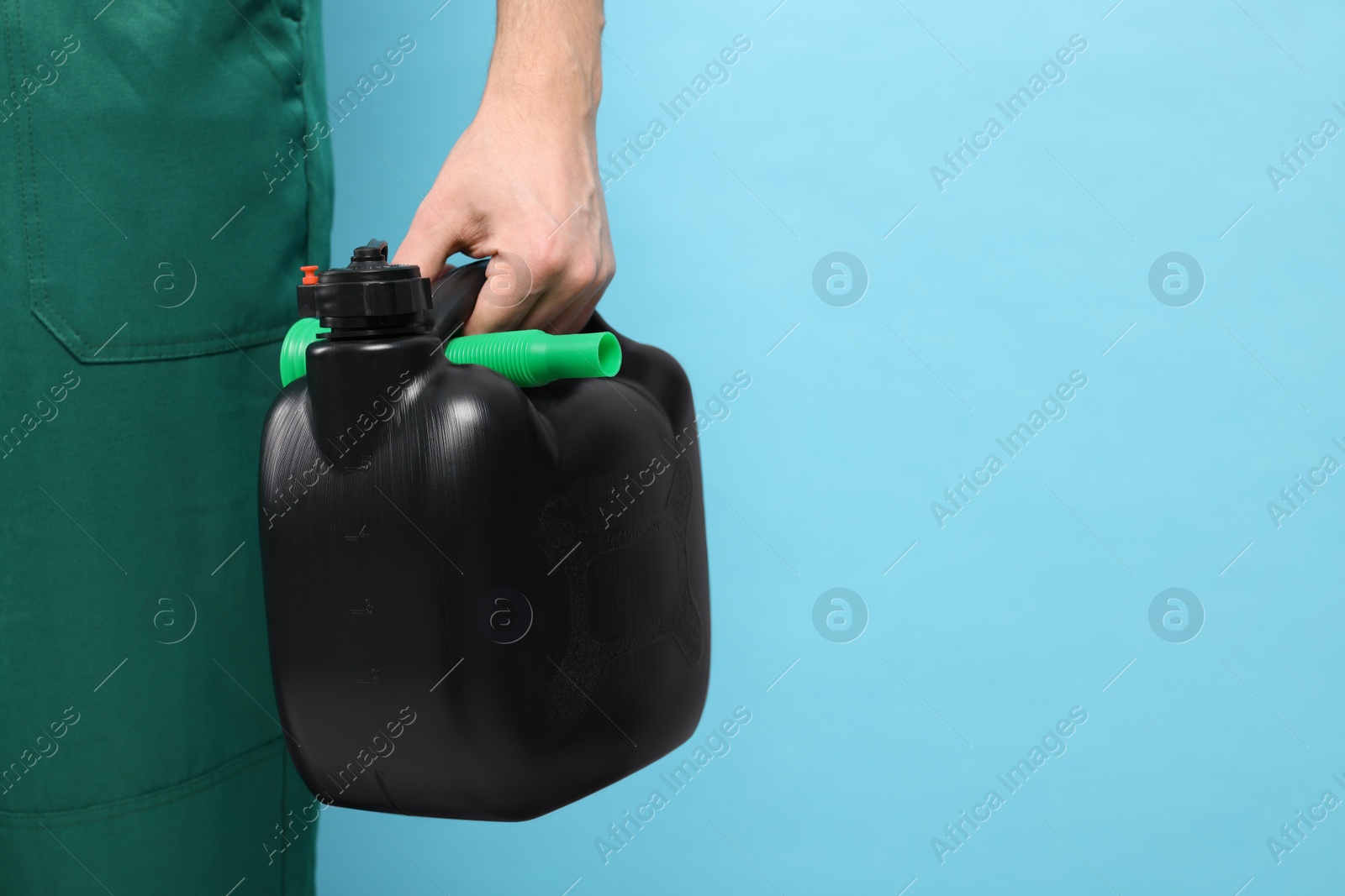Photo of Man holding black canister on light blue background, closeup. Space for text