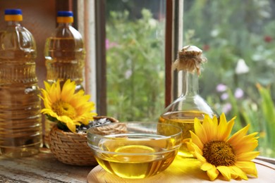 Organic sunflower oil and flower on window sill indoors, space for text