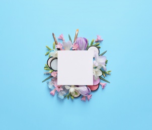 Photo of Makeup products, spring flowers and blank card on color background, flat lay. Space for text