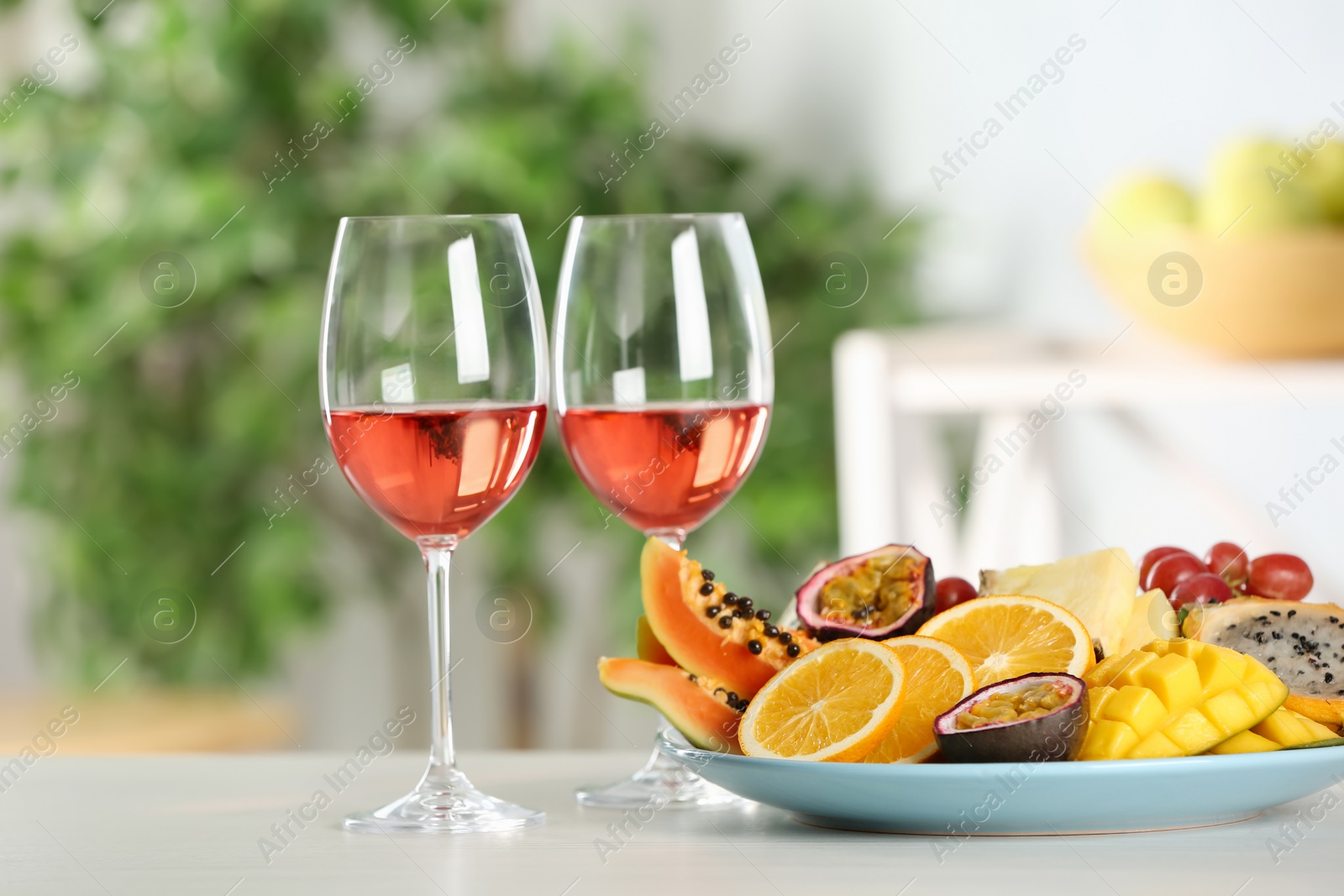 Photo of Delicious exotic fruits and glasses of wine on white table indoors