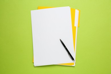 Photo of Yellow file with blank sheets of paper and pen on light green background, top view. Space for design