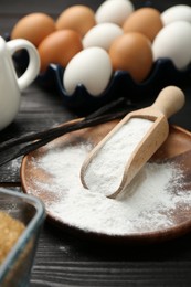 Baking powder and eggs on black wooden table, closeup