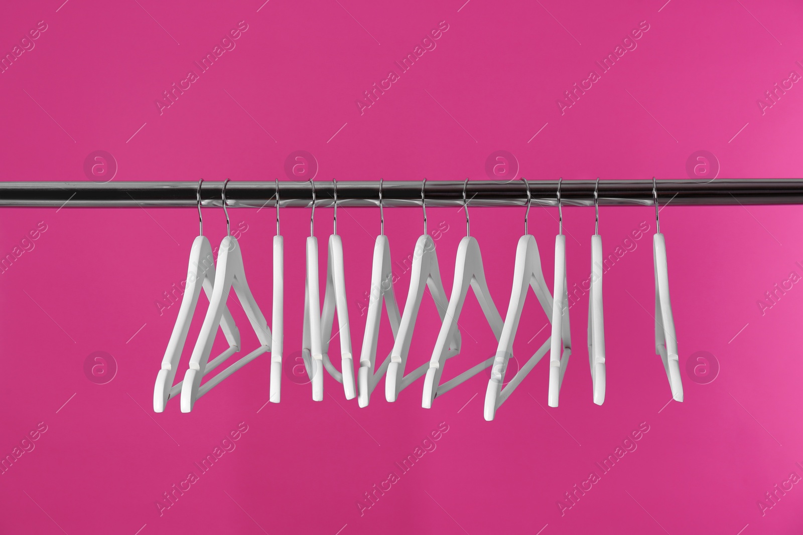 Photo of Metal rack with clothes hangers on color background