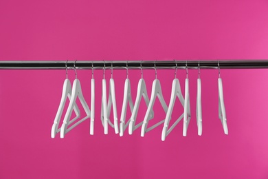 Photo of Metal rack with clothes hangers on color background