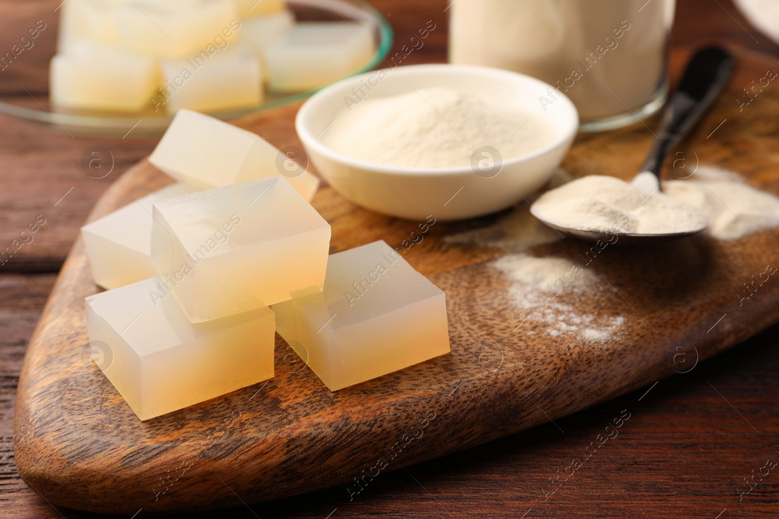 Photo of Agar-agar jelly cubes and powder on wooden table, closeup