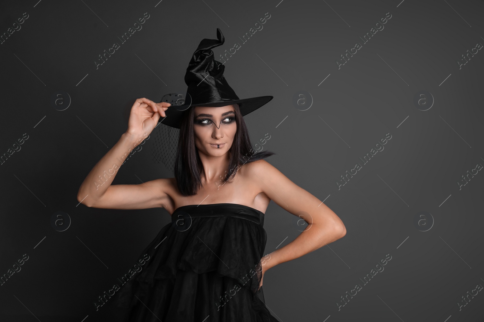 Photo of Mysterious witch wearing hat on black background