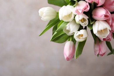 Photo of Beautiful bouquet of tulips against beige background. Space for text