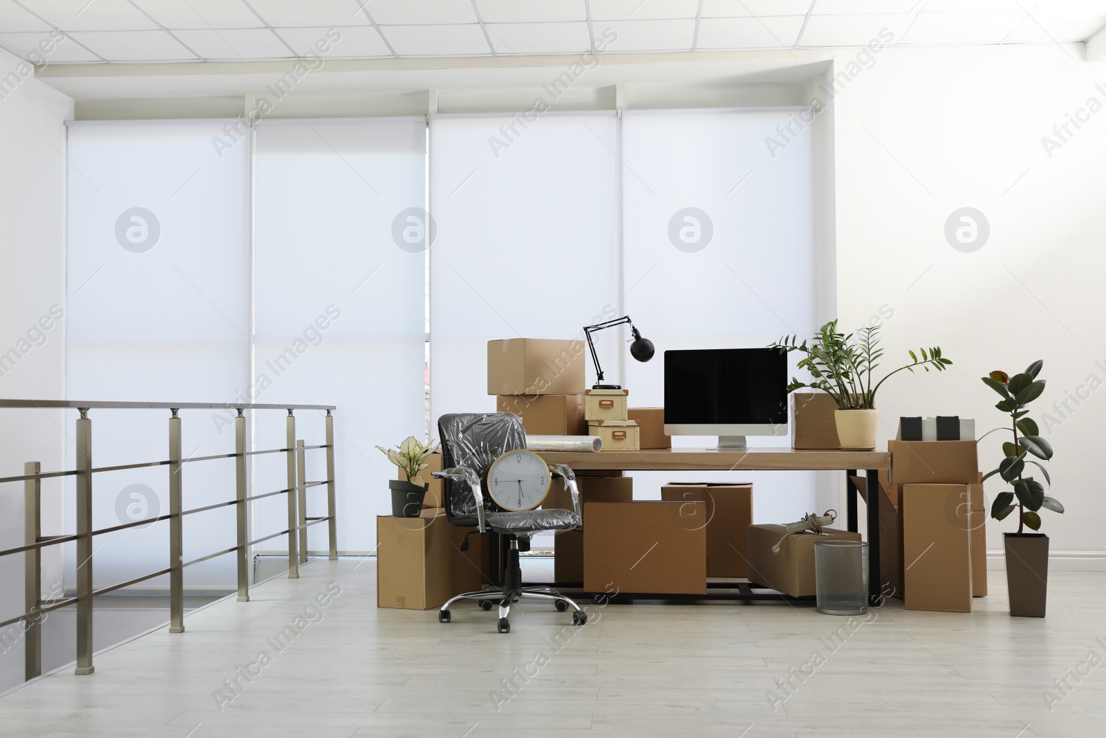 Photo of Cardboard boxes, computer and furniture in new office. Moving day